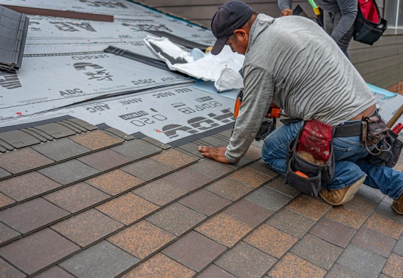 Skilled roofer installing asphalt shingles, ensuring quality home renovation.