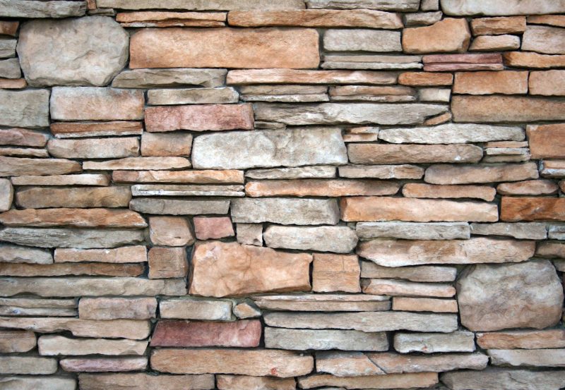 High-resolution image of a natural stone wall with various textures and earthy tones.